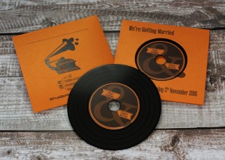 Wedding invite CDs in metallic orange recycled record-style wallets with black vinyl discs