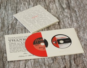 Four page double disc vinyl CD wallet with two vinyl discs stacked on top of each other using both red and black record-style discs